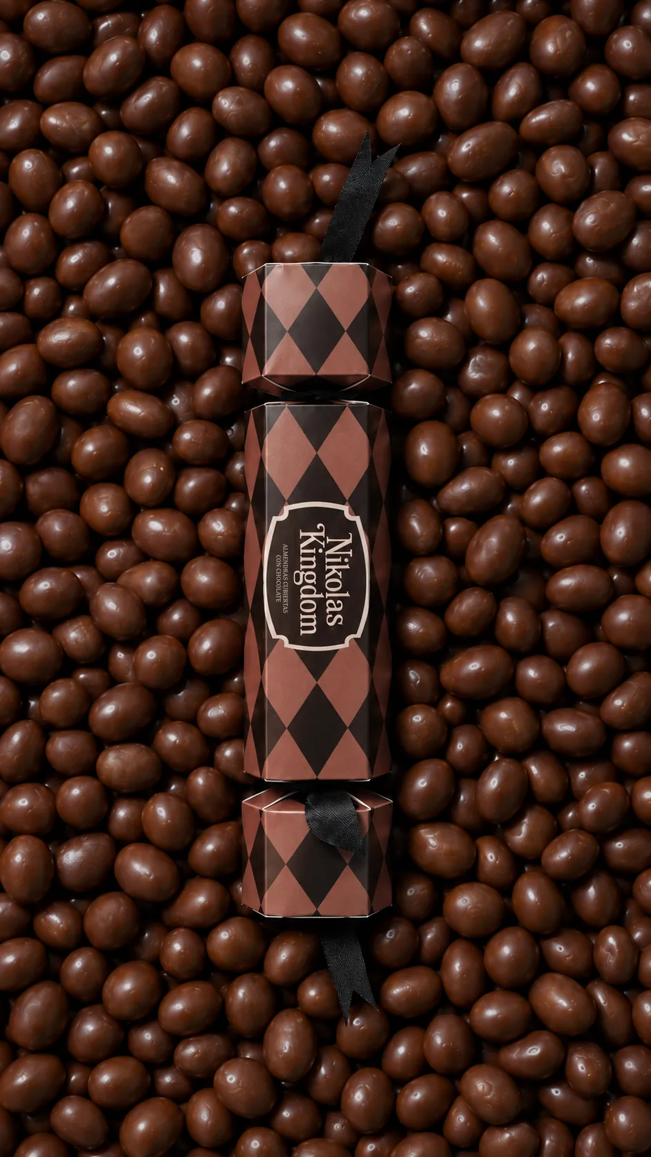 Detalle de grageas de chocolate alrededor de un estuche café con patrón de arlequín.